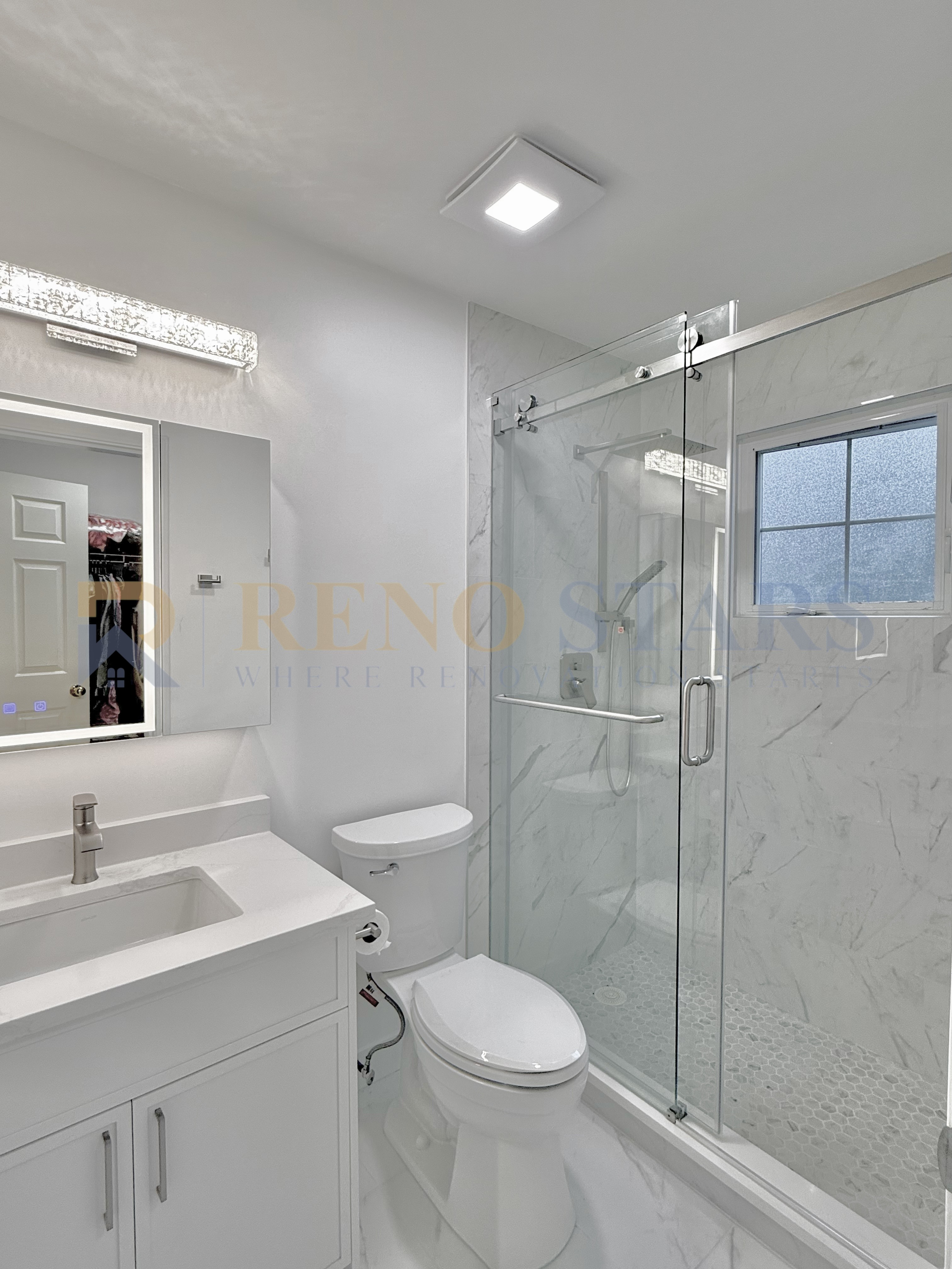 Modern bathroom featuring a glass shower, white vanity, and sleek lighting.
