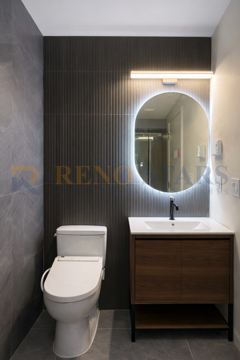 Modern bathroom featuring a sleek toilet, wooden vanity, and illuminated mirror.