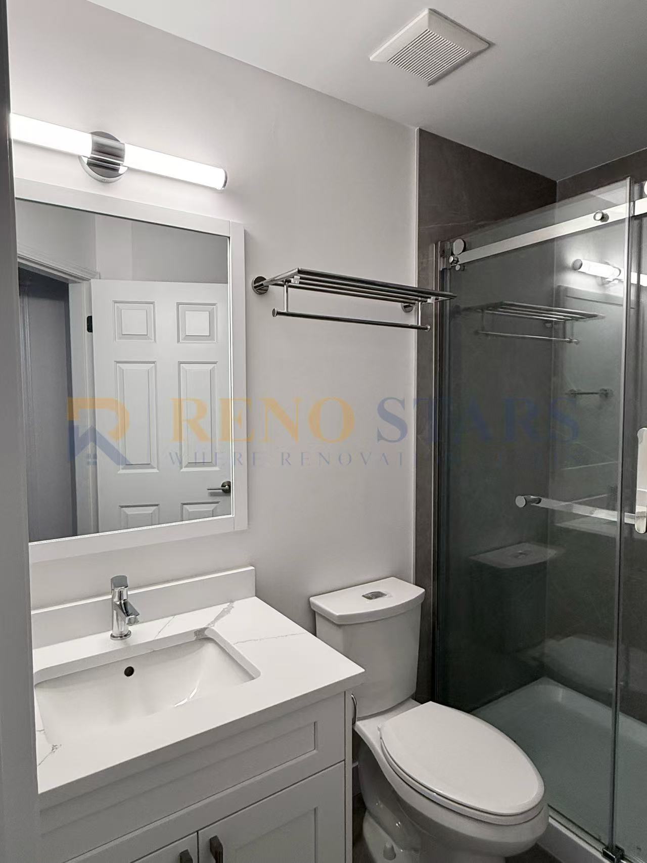 Modern bathroom featuring a glass shower, sleek vanity, and contemporary lighting.