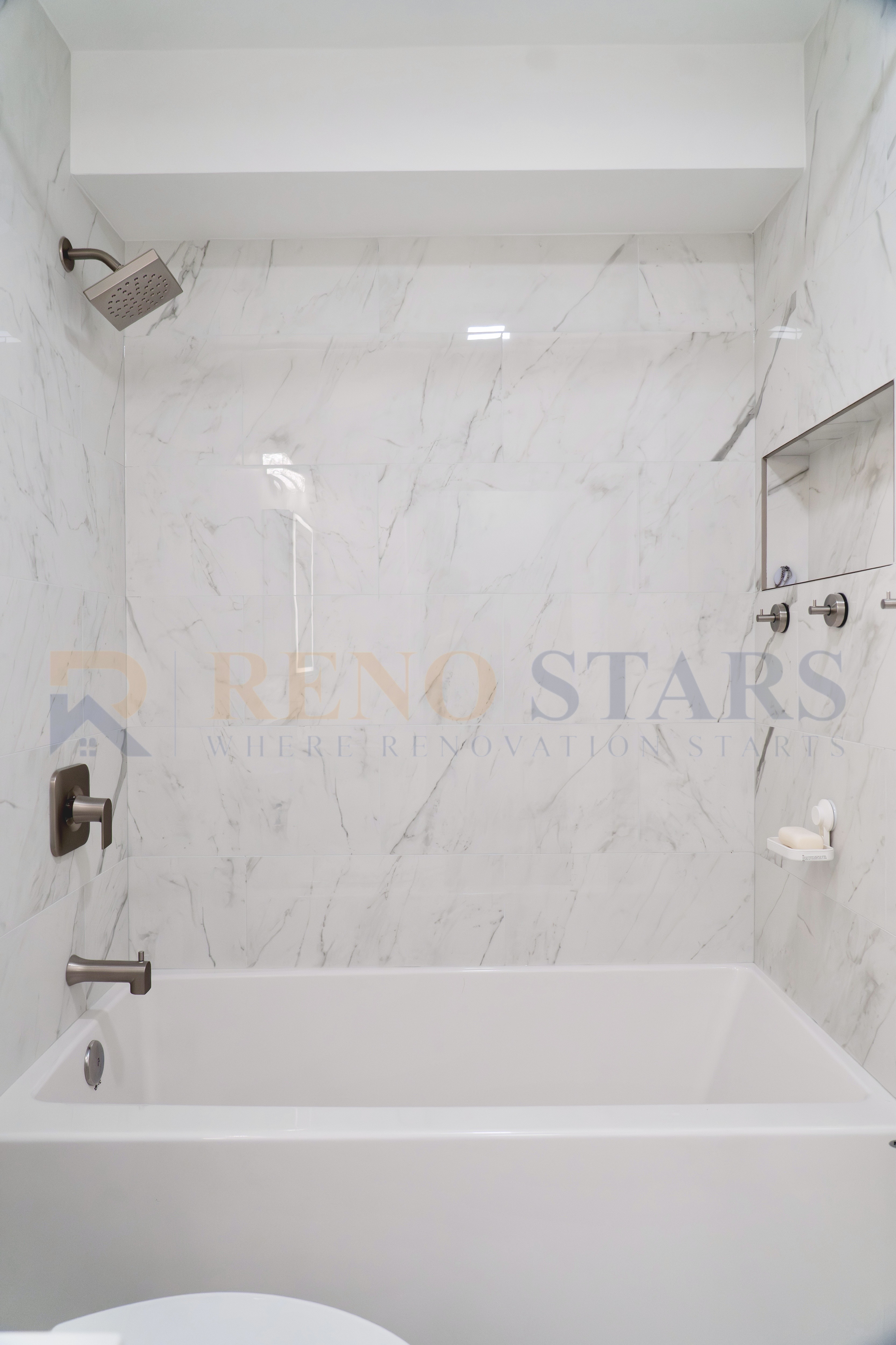 Modern bathroom featuring a white tub and elegant marble walls with a showerhead.
