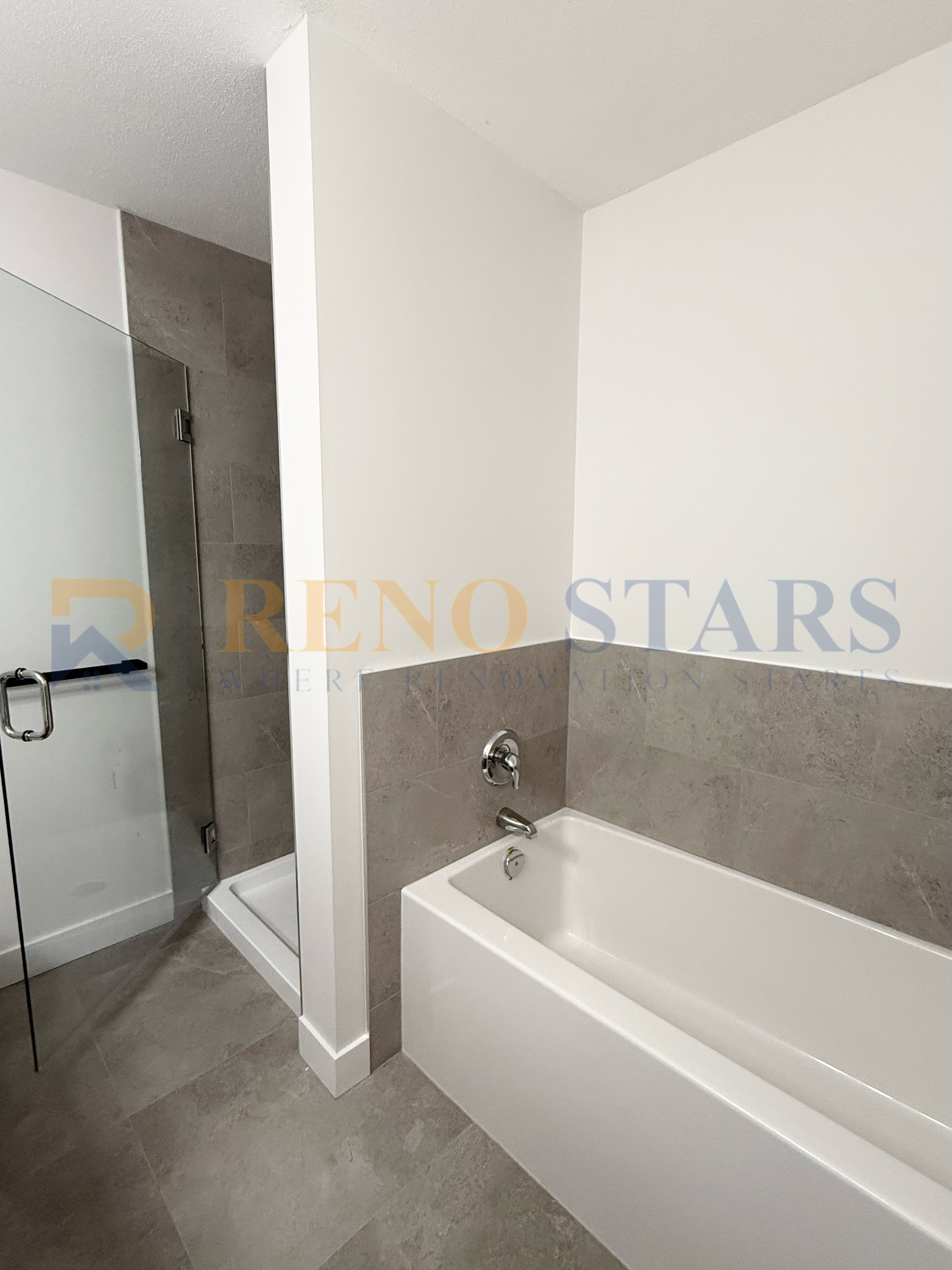 现代浴室，配有光滑的浴缸和玻璃淋浴间，采用中性色调瓷砖。