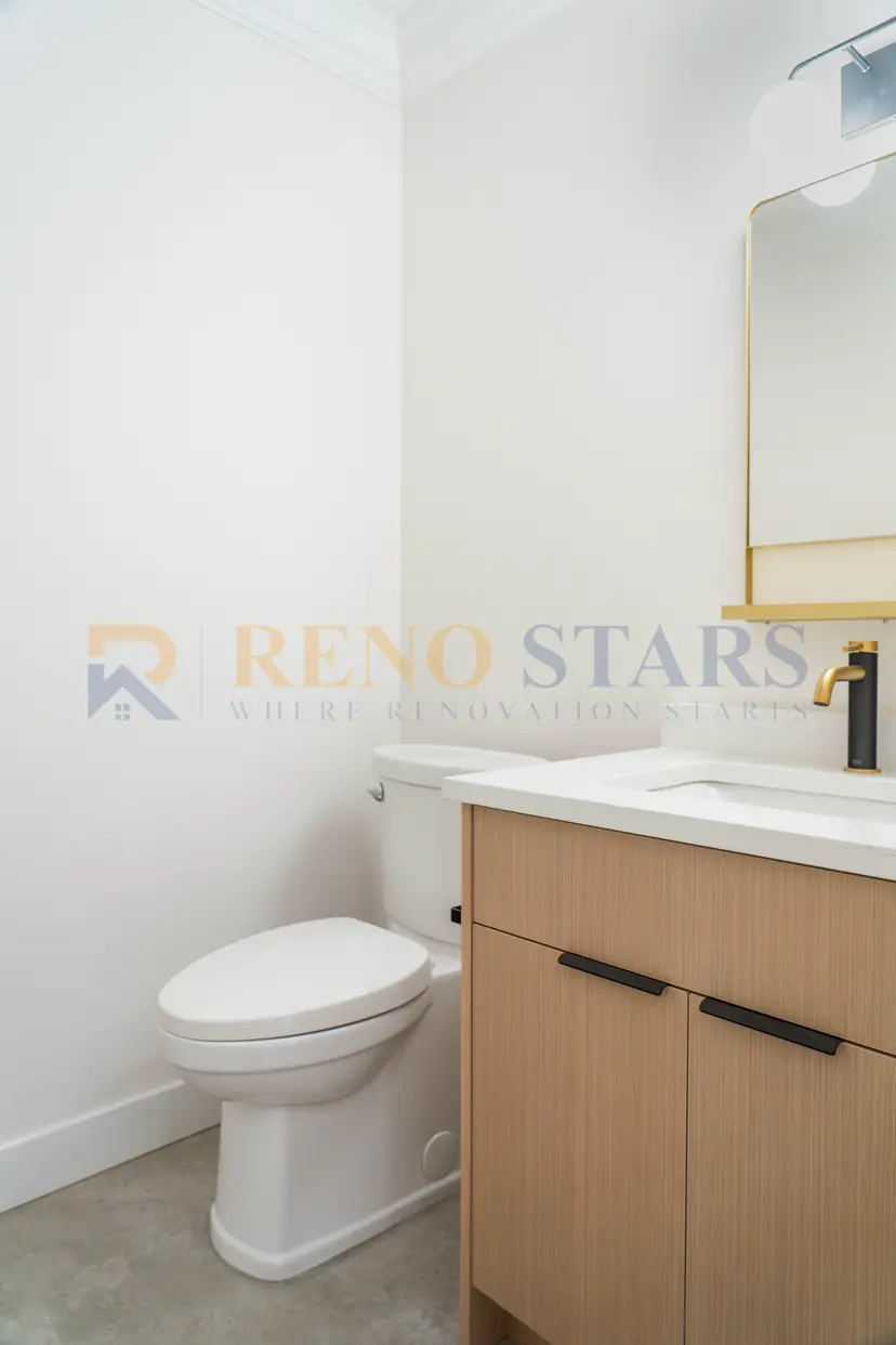 Modern bathroom featuring a white toilet, wooden vanity, and stylish lighting.