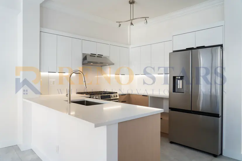 Modern kitchen with white cabinetry, stainless steel appliances, and a marble countertop.